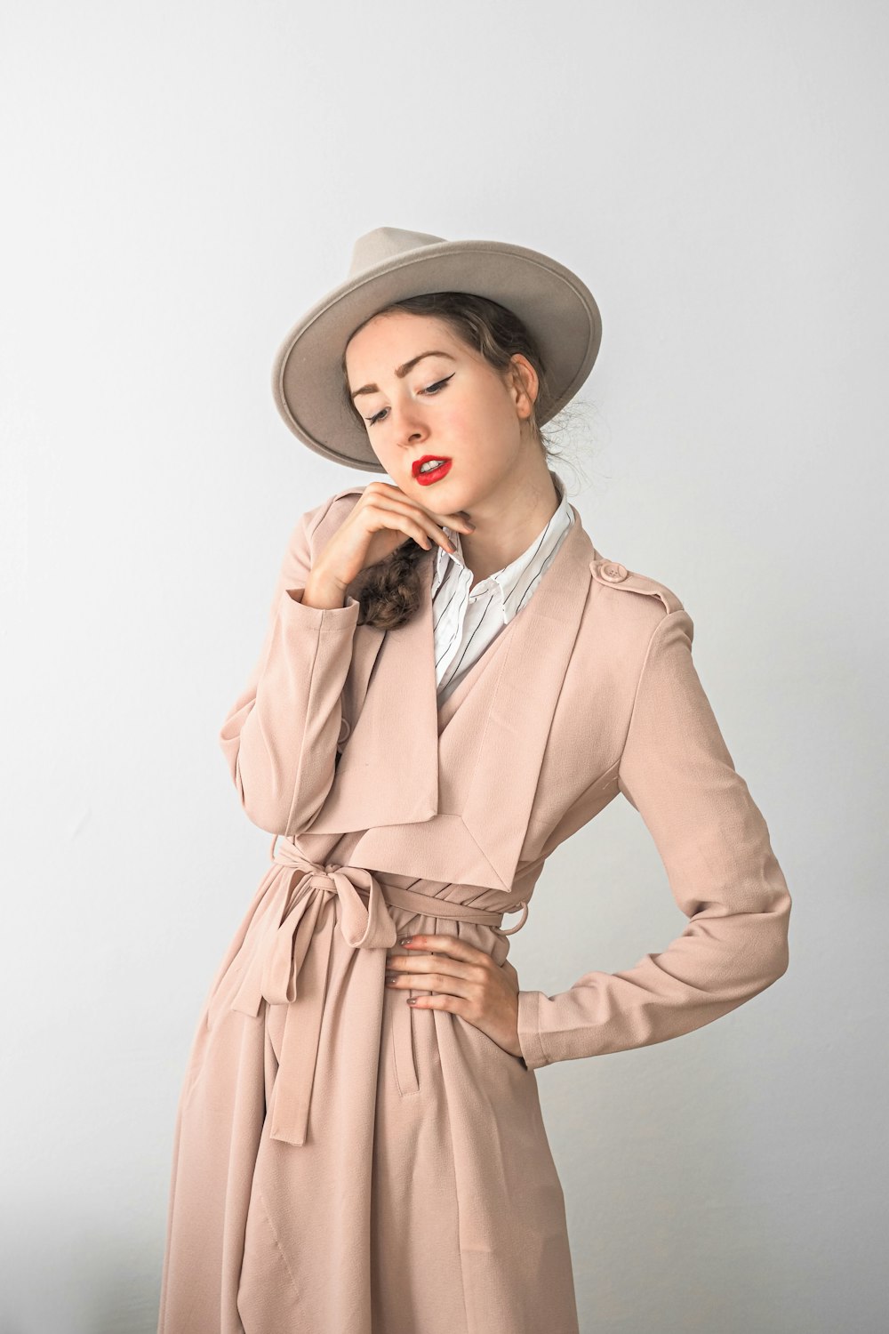 a woman in a trench coat and hat poses for a picture