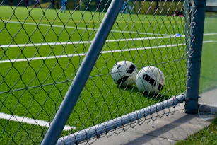 a soccer ball sitting on the ground behind a fence