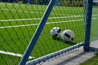 a soccer ball sitting on the ground behind a fence