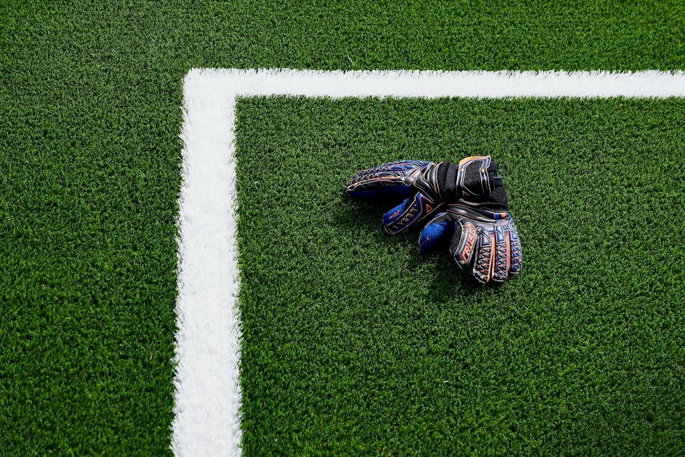 luva de um goleiro de futebol deitada em um campo de futebol