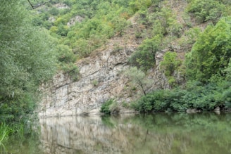 A serene Ardèche landscape with gentle hills and a calm river, reflecting the peaceful environment of sn-naturopathie's practice.