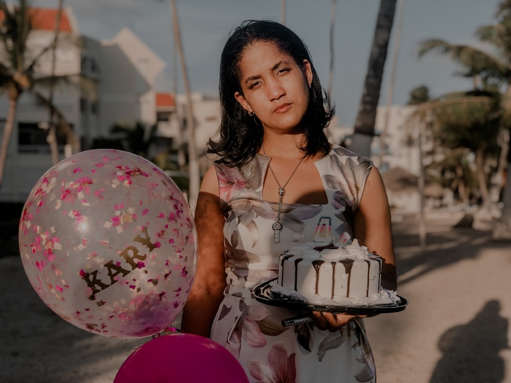 Une femme tenant un gâteau d’anniversaire et des ballons