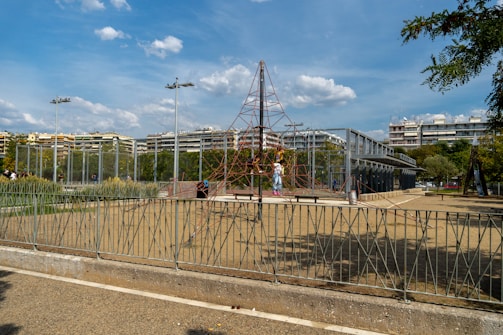 A playground safety inspector examining surfacing under climbing equipment on a sunny day.