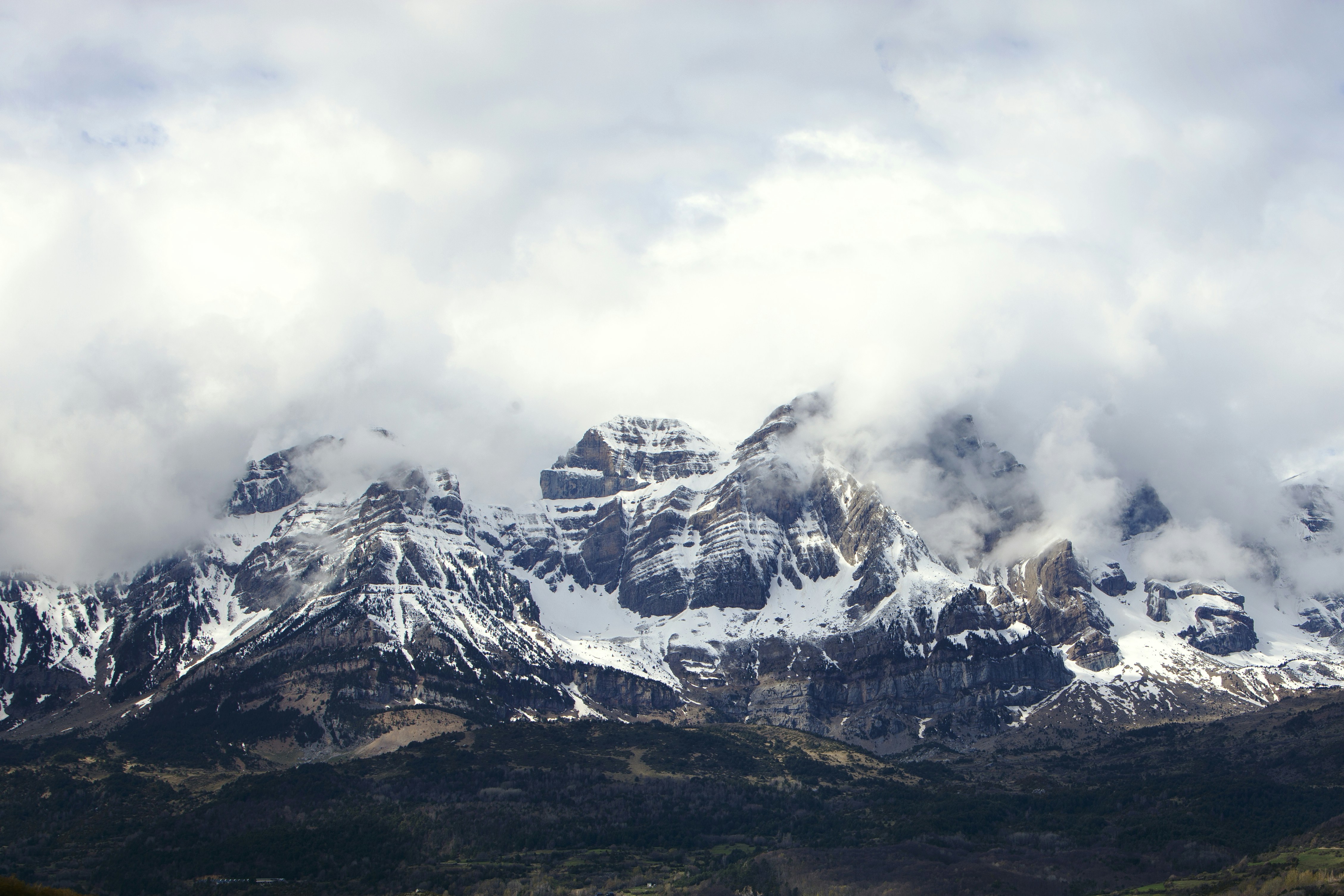 a mountain range covered in snow and clouds
