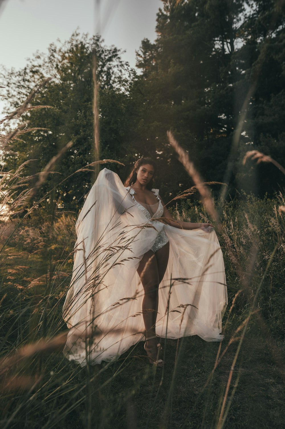 a woman in a white dress standing in tall grass