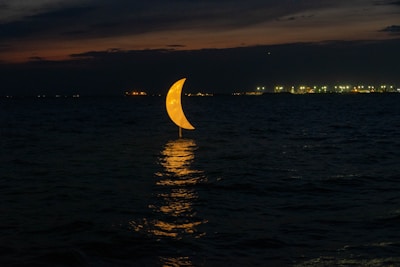 A glowing crescent moon rises over a futuristic cityscape glowing with neon blues and purples.