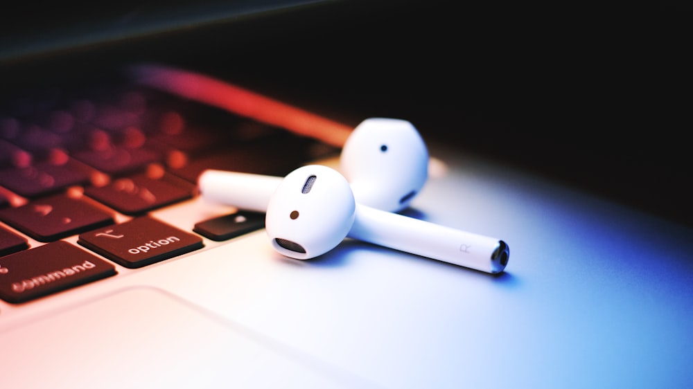 a pair of ear buds sitting on top of a laptop keyboard