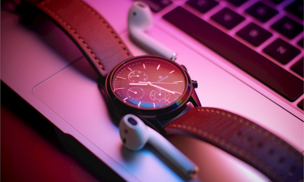 a watch sitting on top of a laptop computer