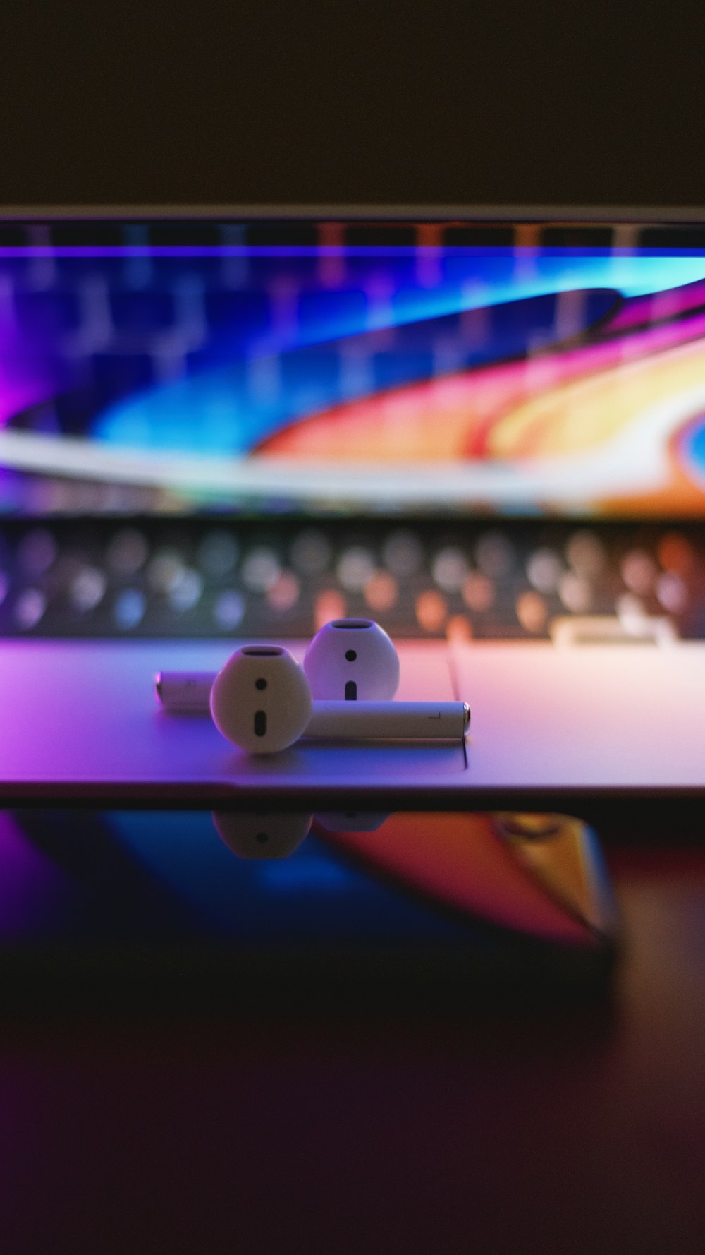 a pair of white ear buds sitting on top of a laptop