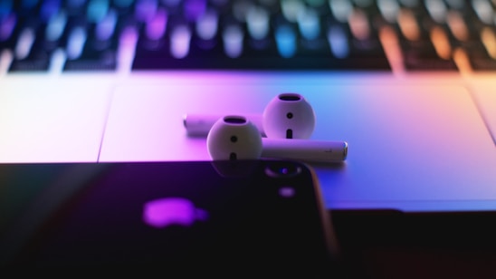 Close-up of a sleek bronurd wireless audio device resting on a wooden desk, bathed in soft natural light.