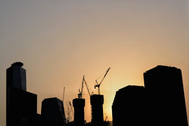 City skyline with cranes and construction sites at sunset.