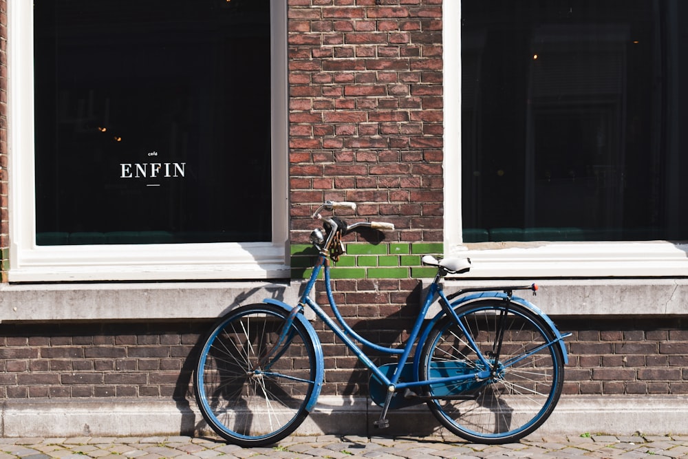 a blue bicycle parked in front of a brick building
