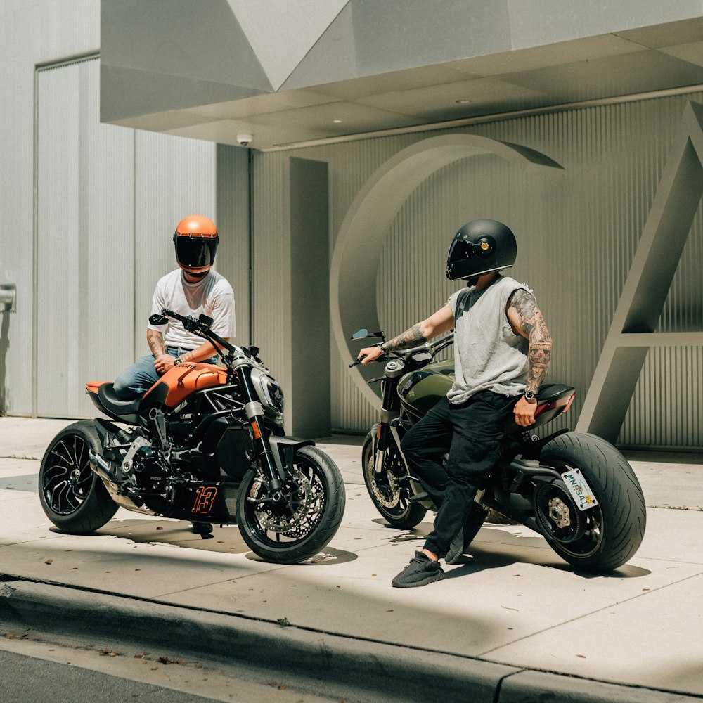 two men sitting on motorcycles on a city street