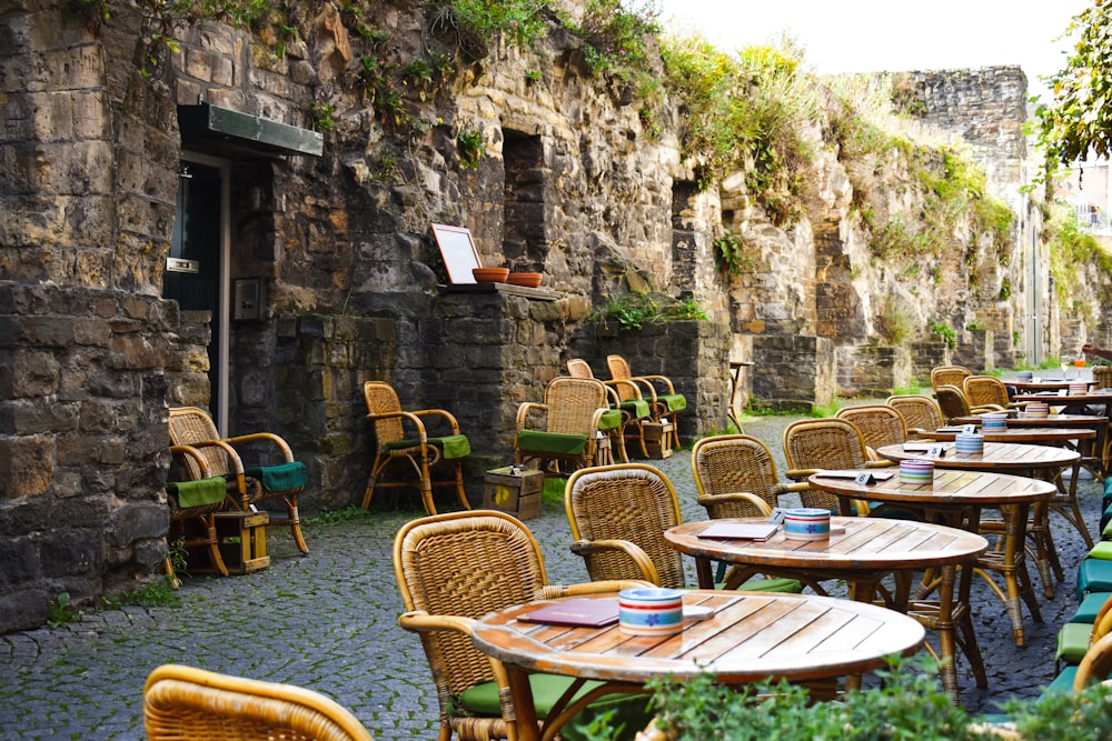 a row of tables and chairs sitting next to a stone wall