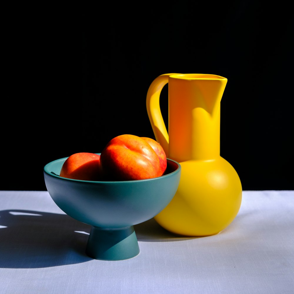 a yellow pitcher and a blue bowl of fruit