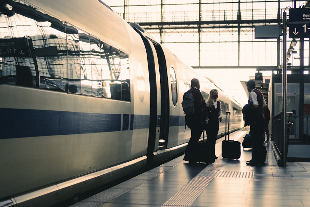 a group of people standing next to a train