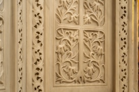 Intricate stone carving featuring detailed floral patterns and symmetrical designs. The craftsmanship shows a high level of artistry with delicate curves and textured surfaces.