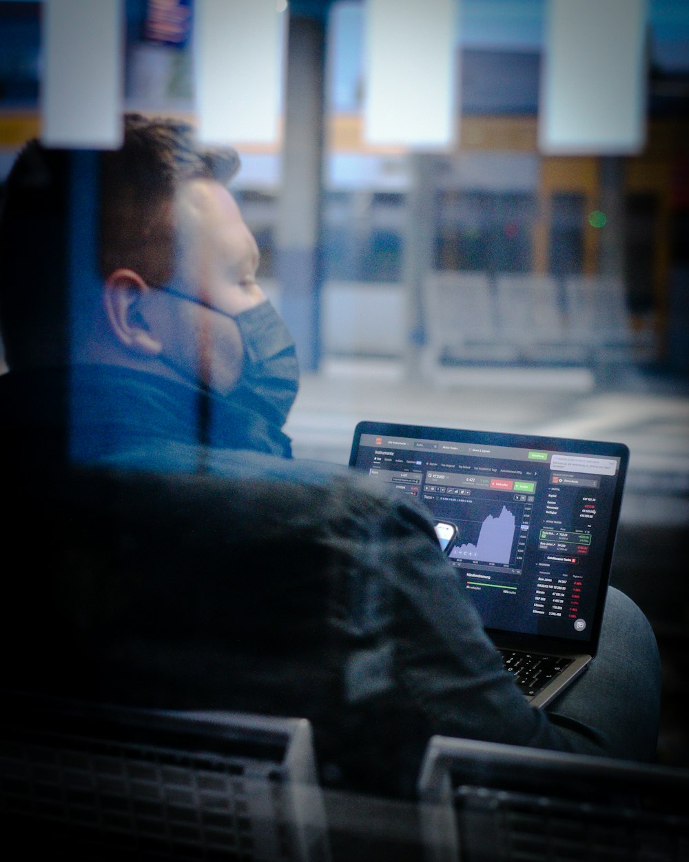 a man sitting on a bus looking at his laptop