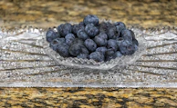 Fresh cranberries and blueberries nestled together in a rustic ceramic bowl.
