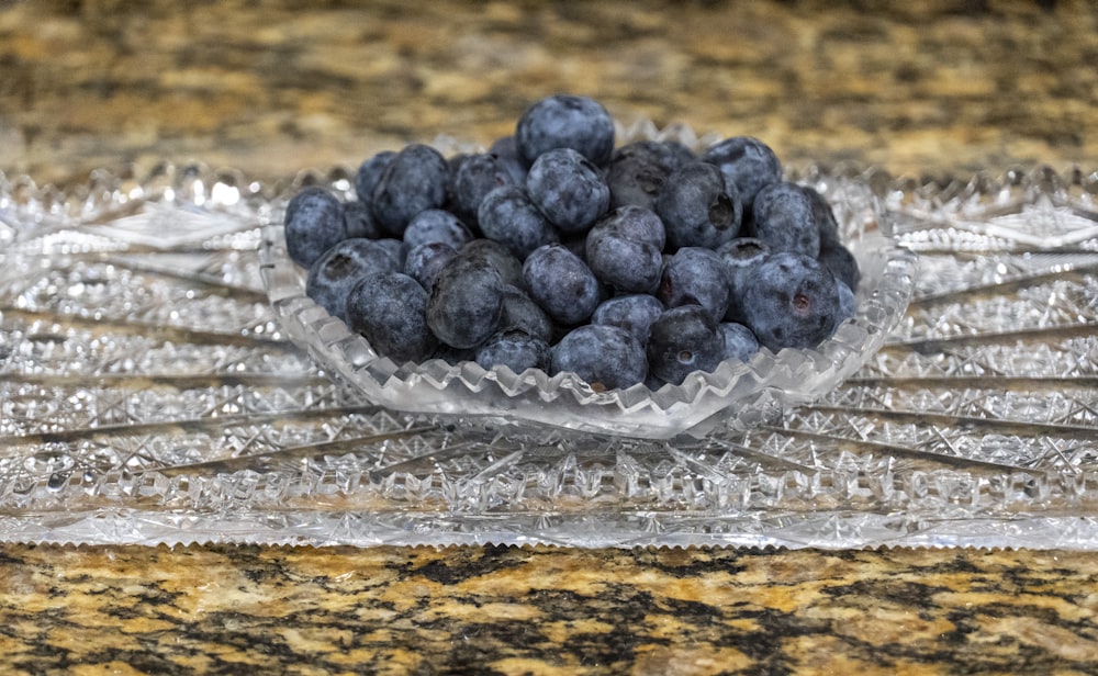 a glass bowl filled with blueberries on top of a counter