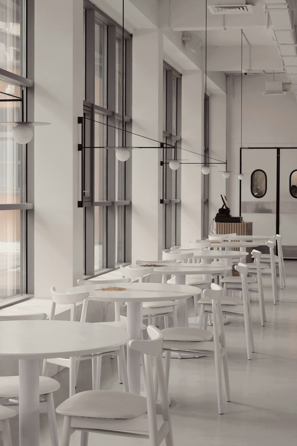 a row of white tables and chairs in a room