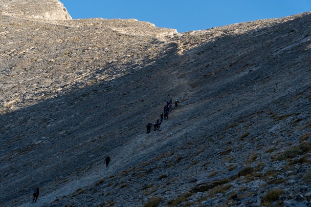 A group of runners crossing a rugged mountain trail at sunrise, with the Miles Coin logo subtly overlaid.