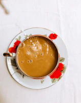 A steaming cup of cha with swirling milk foam, resting beside a rustic wooden table.