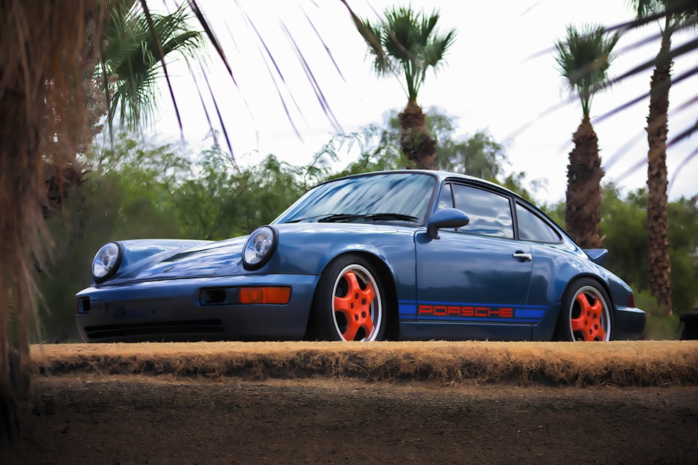 a blue porsche parked in front of palm trees
