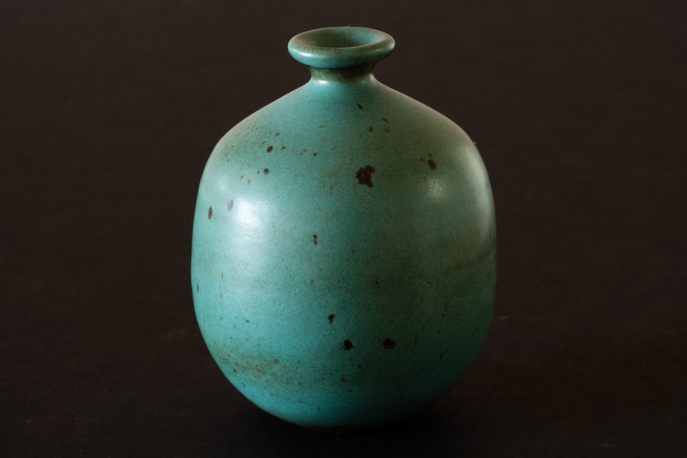 a green vase sitting on a black surface