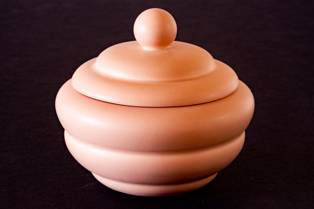 a pink ceramic container sitting on a black surface