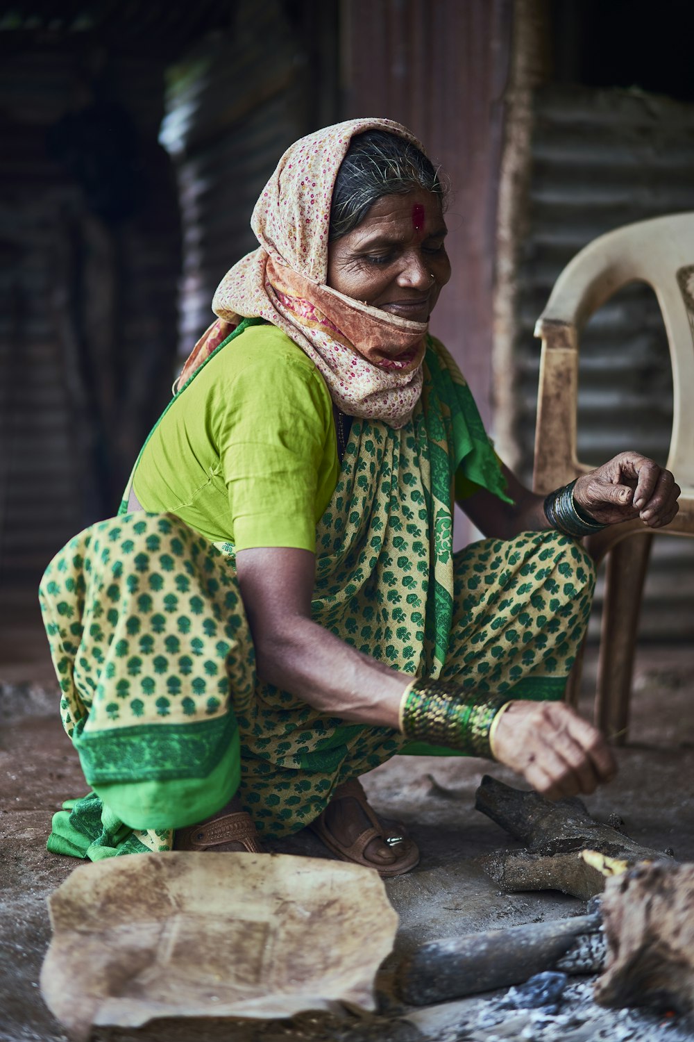 a woman sitting on the ground working on a piece of wood