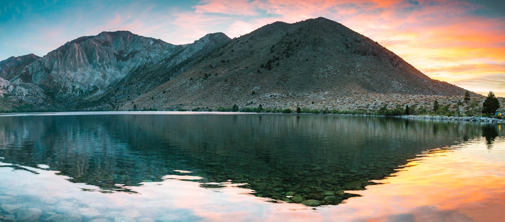 a mountain range is reflected in the still water of a lake