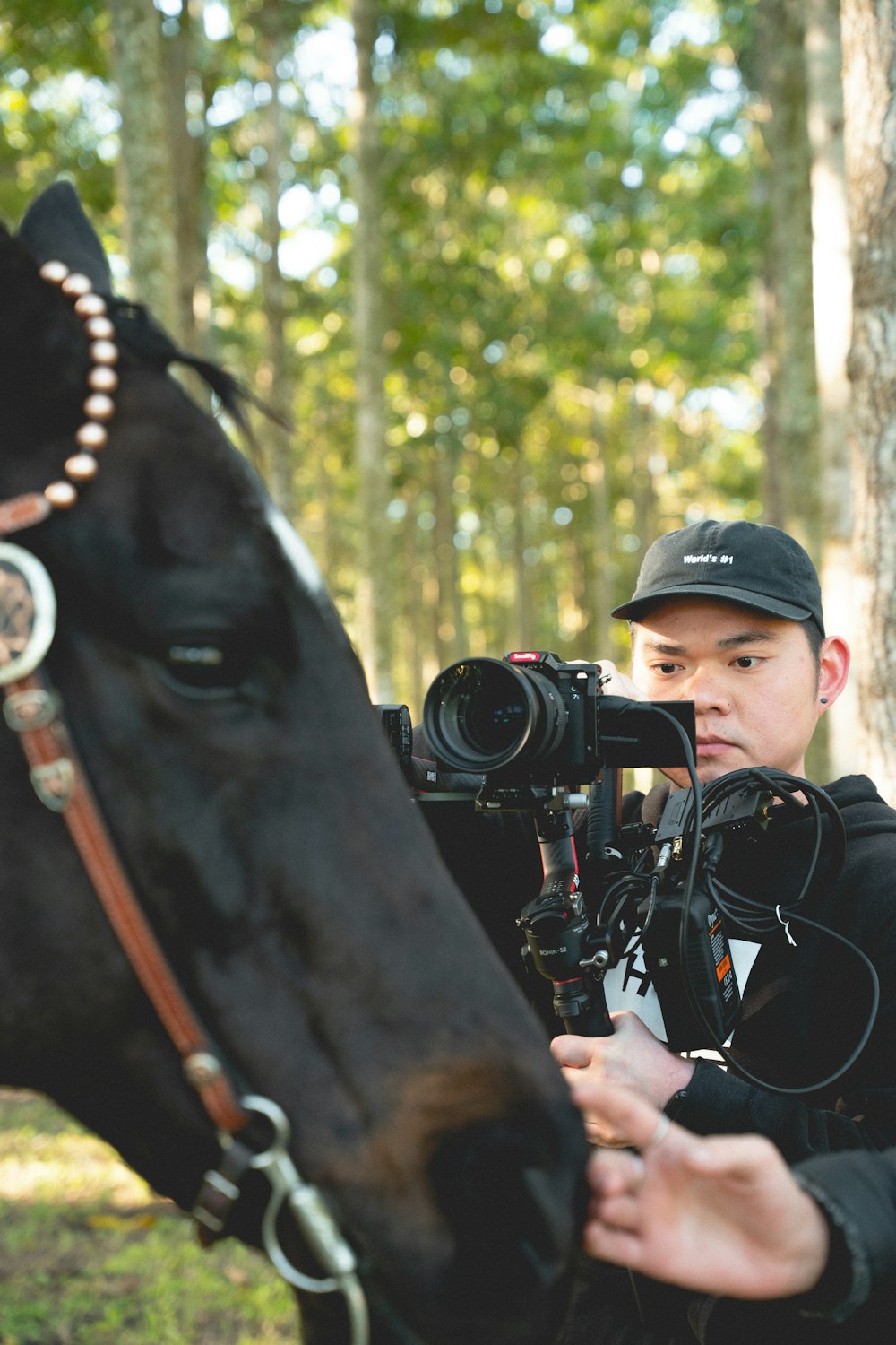 Un hombre parado junto a un caballo sosteniendo una cámara