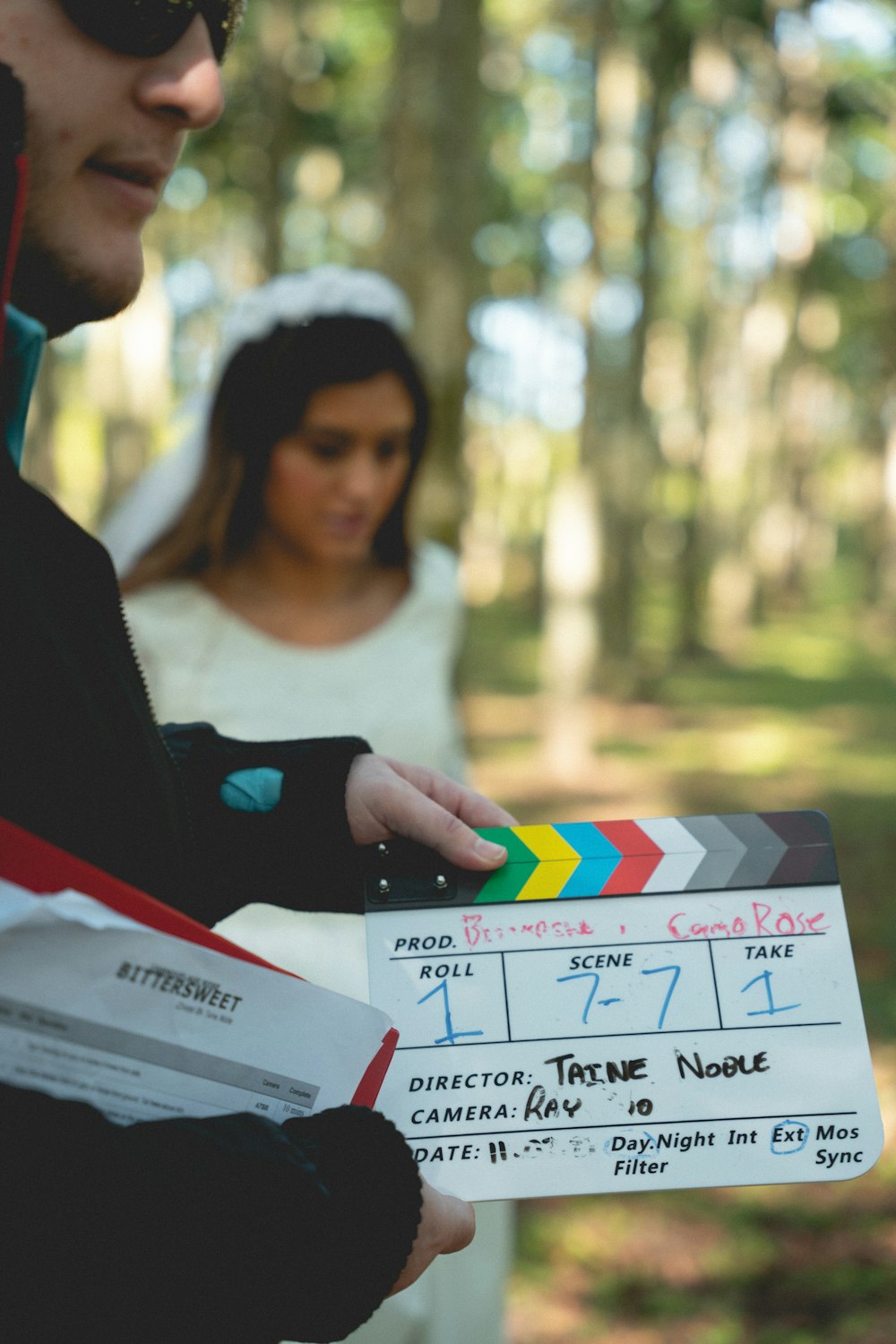 a man and woman holding a clapper in a forest