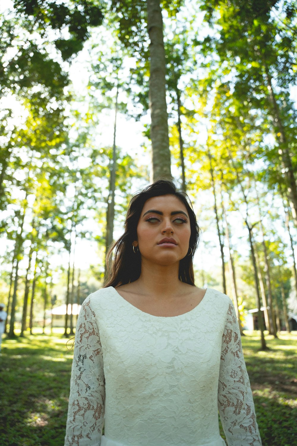 a woman in a white dress standing in a forest