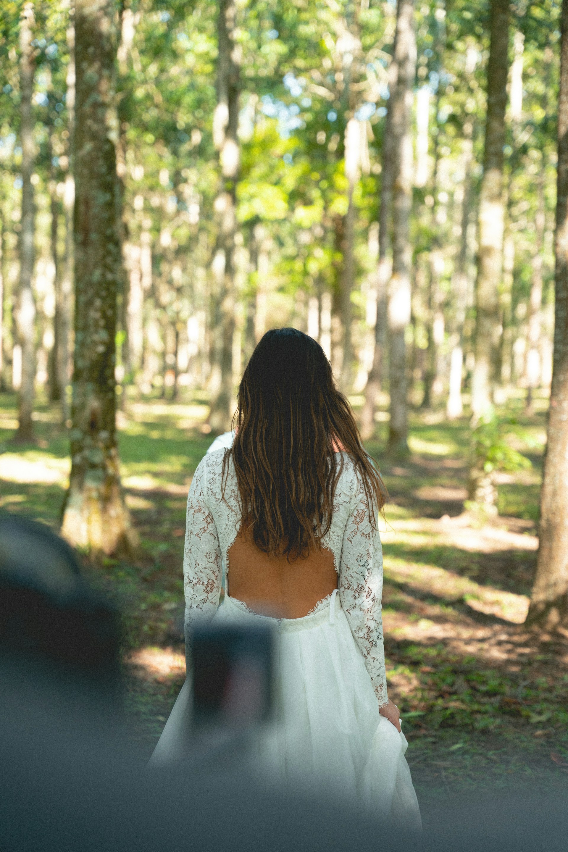 a woman in a white dress walking through a forest