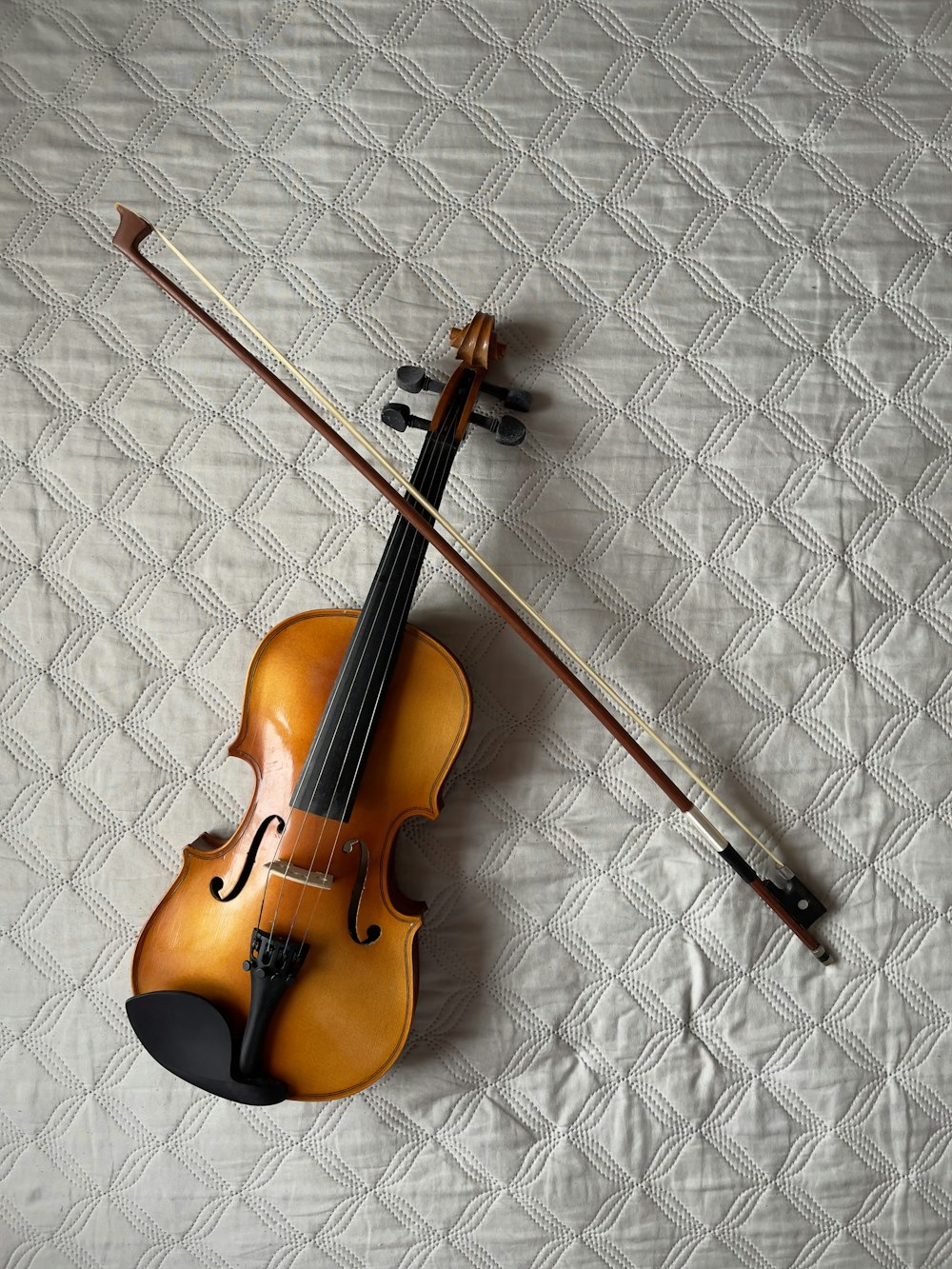 a violin and a bow laying on a bed