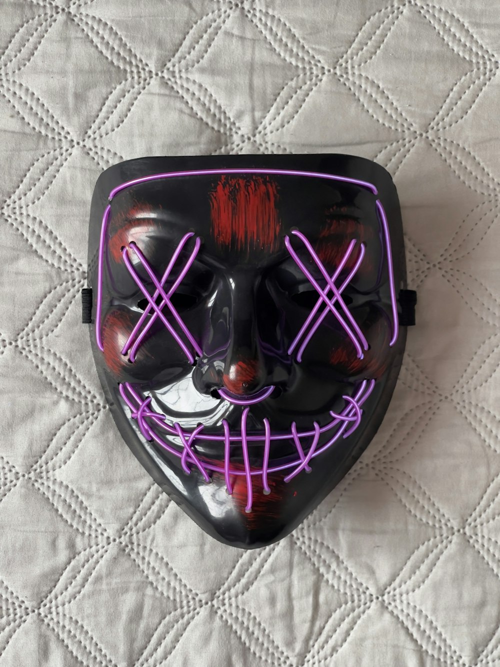 a black mask with purple lines on it