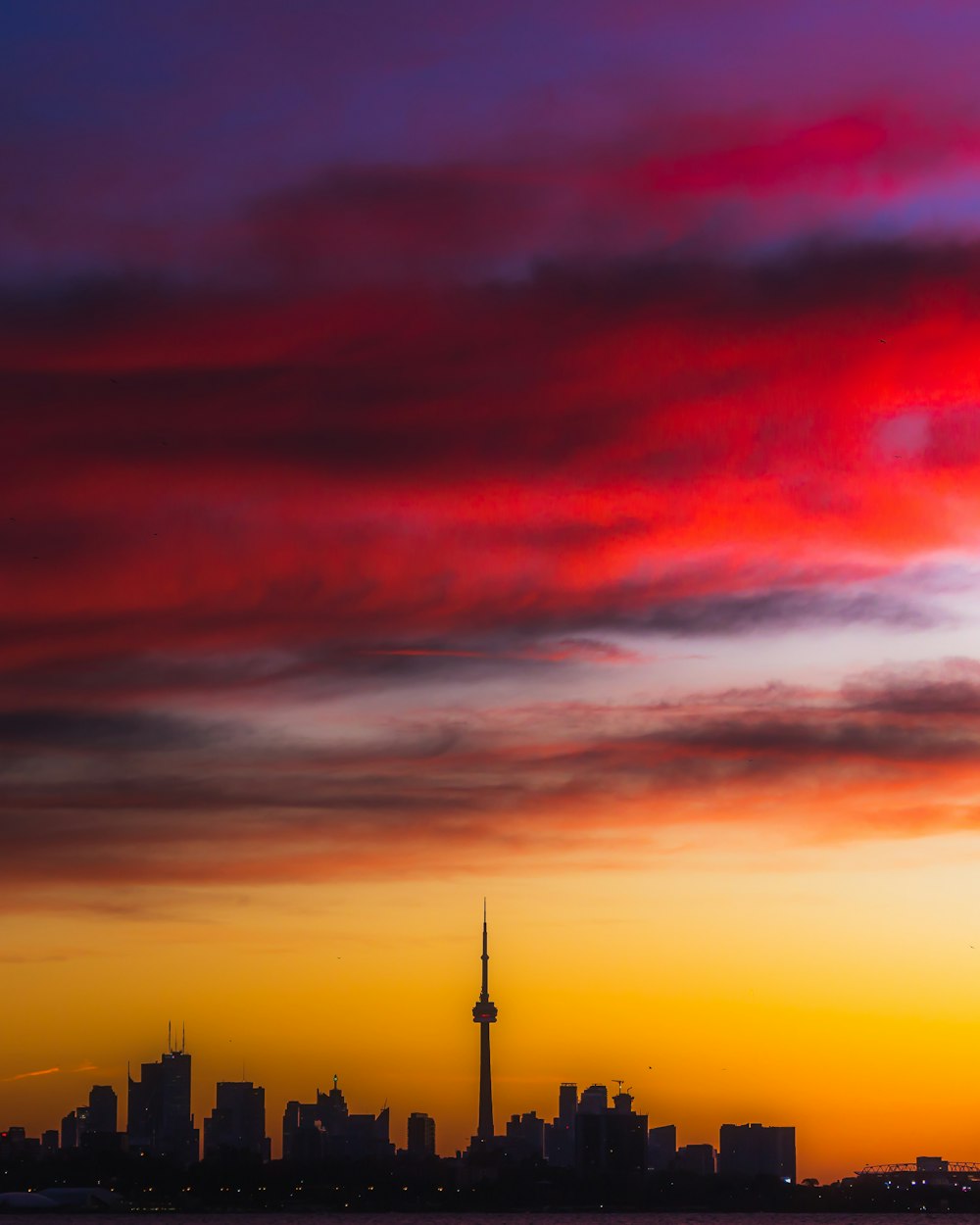 a sunset view of a city with a plane flying in the sky