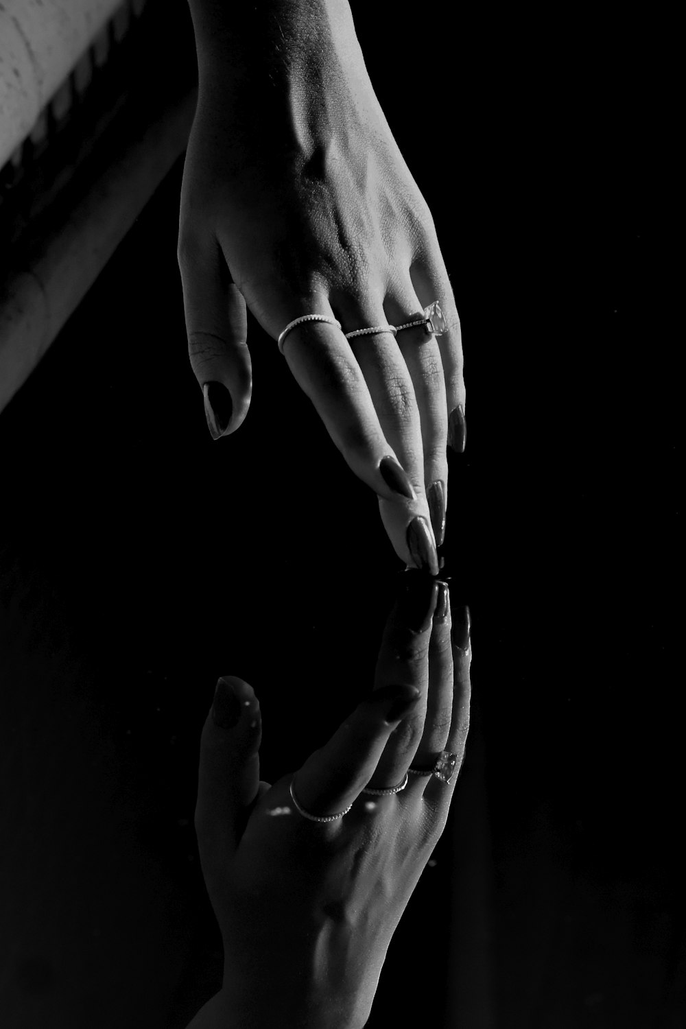 a black and white photo of two hands touching each other