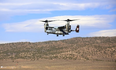 a large military helicopter flying over a field