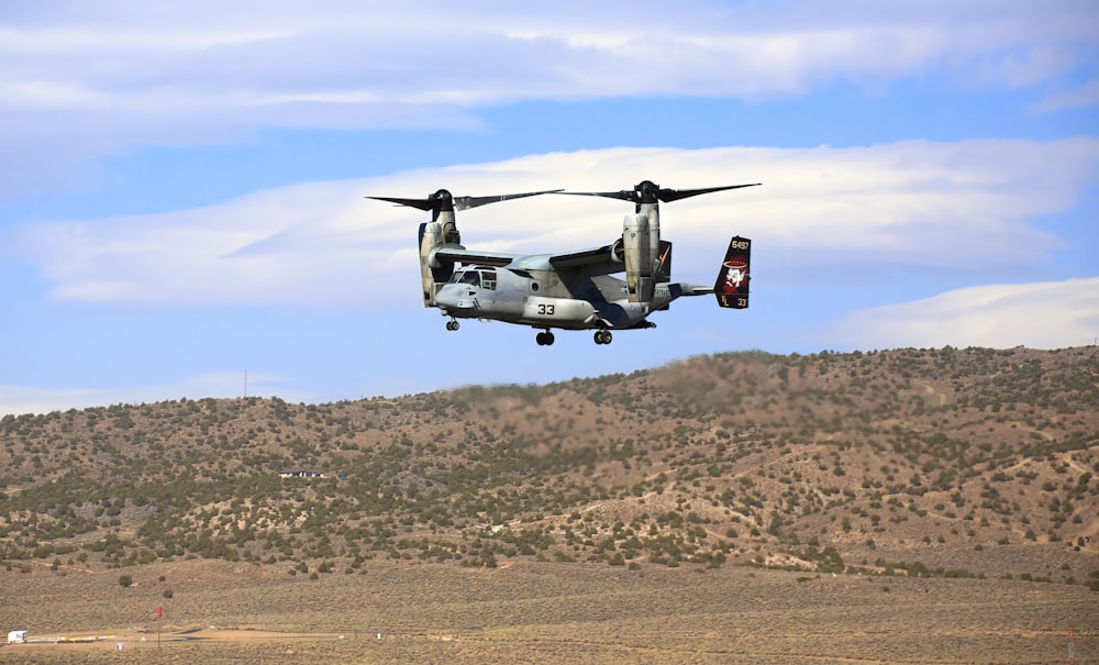 a large military helicopter flying over a field