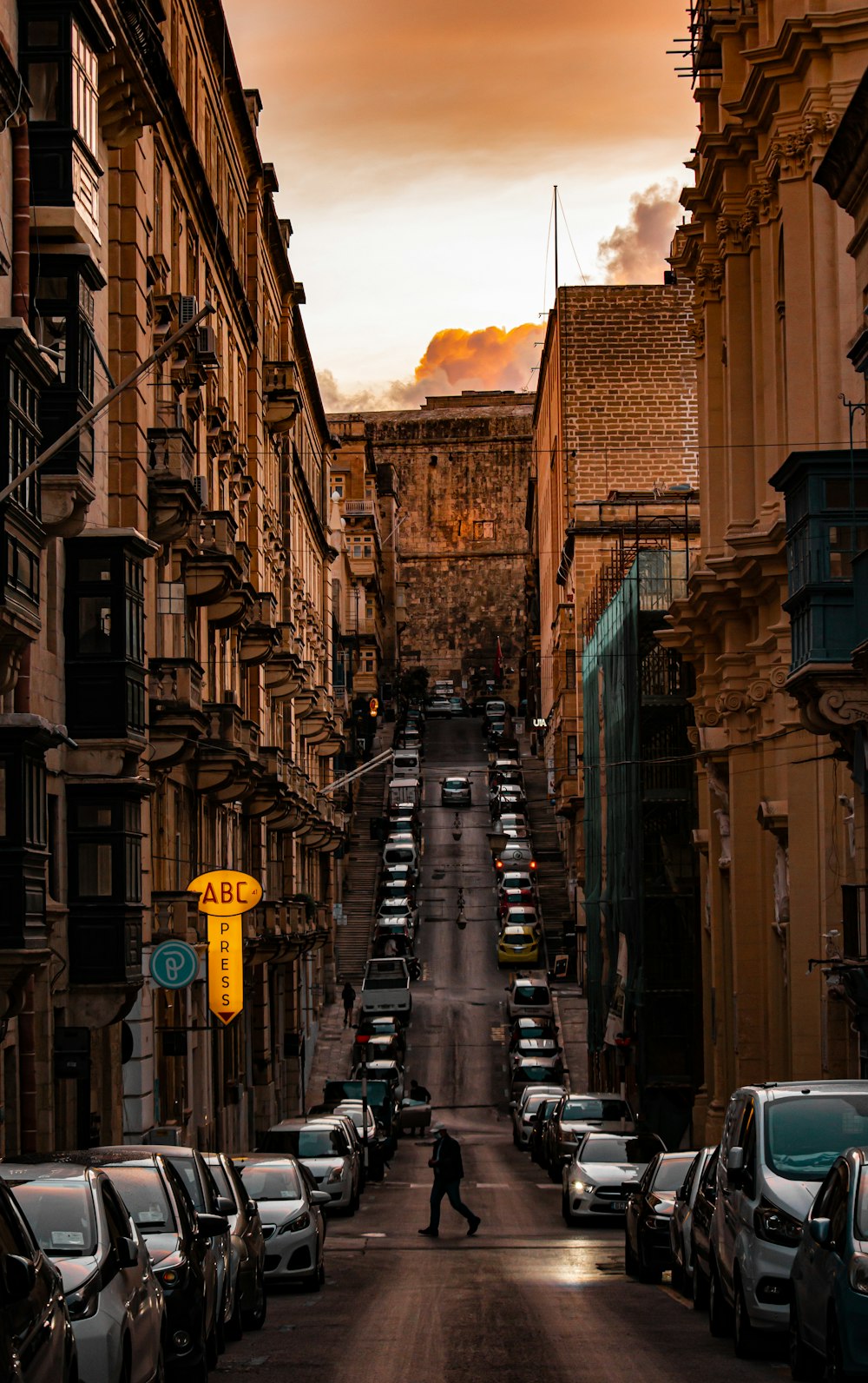 a man walking down a street next to parked cars