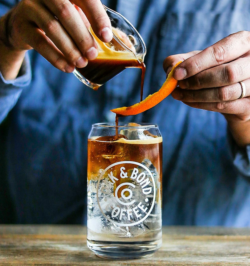 a person pouring a drink into a glass