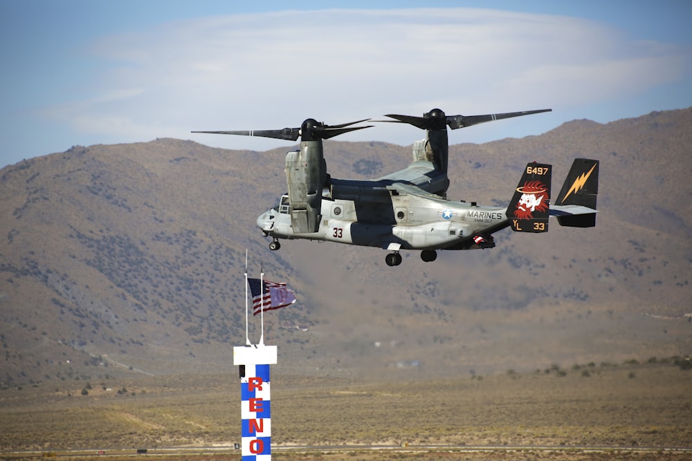 a military helicopter flying over a flag pole