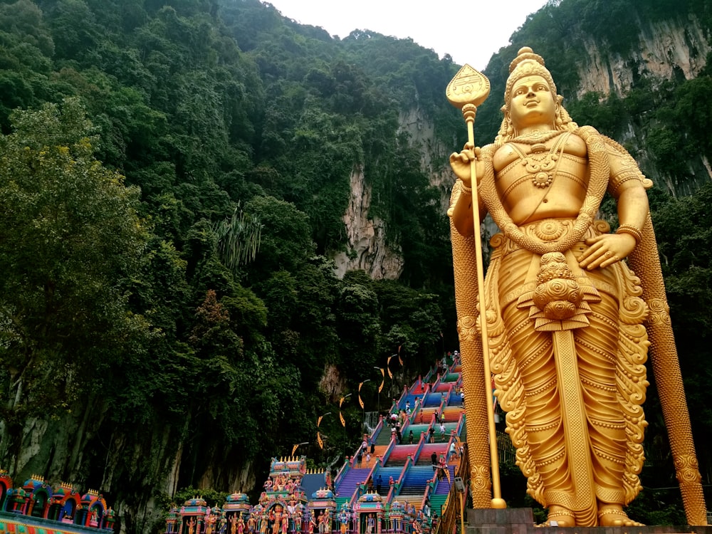 a statue of a man holding a staff in front of a mountain