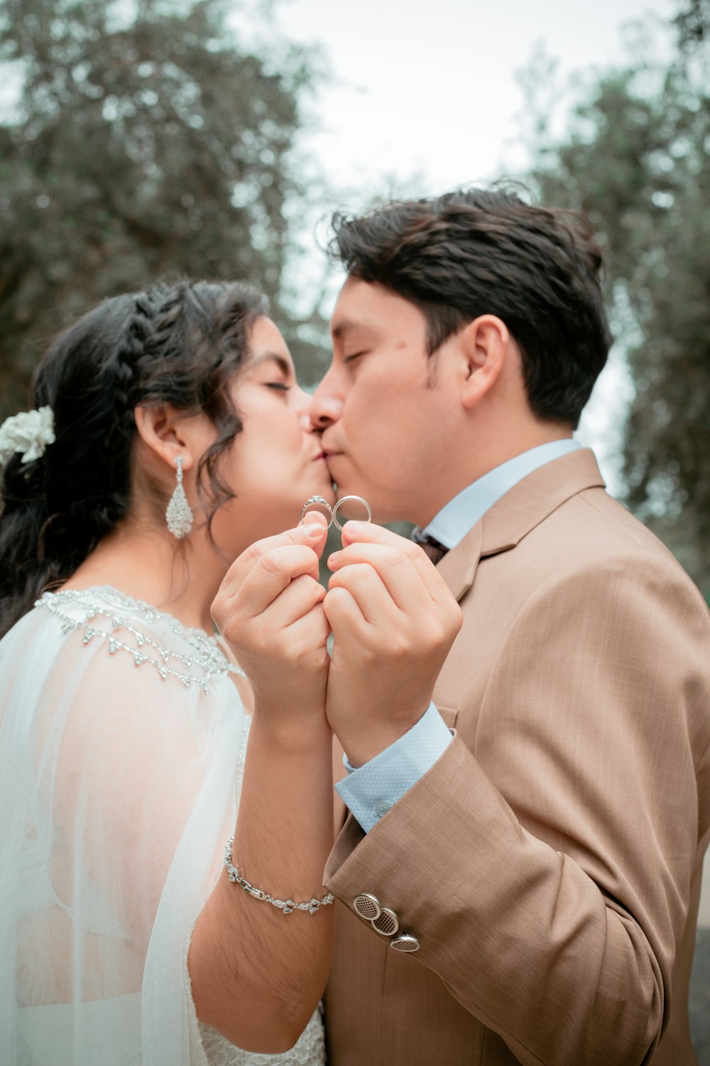 uma noiva e noivo se beijando na frente das árvores