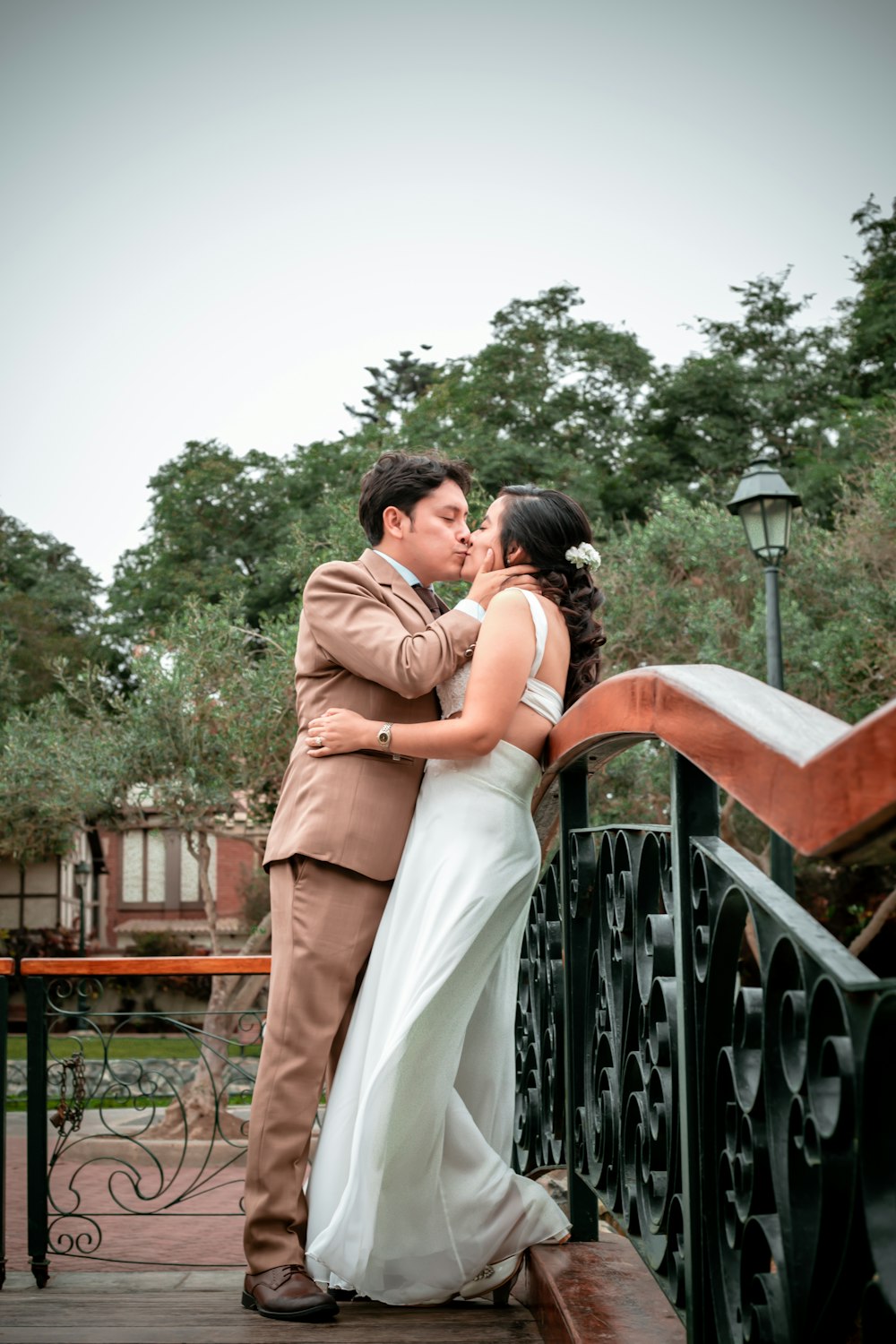 a bride and groom kissing on a bridge