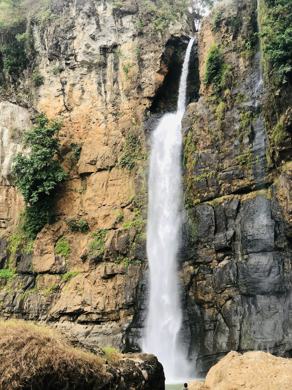 a waterfall with a man standing in front of it