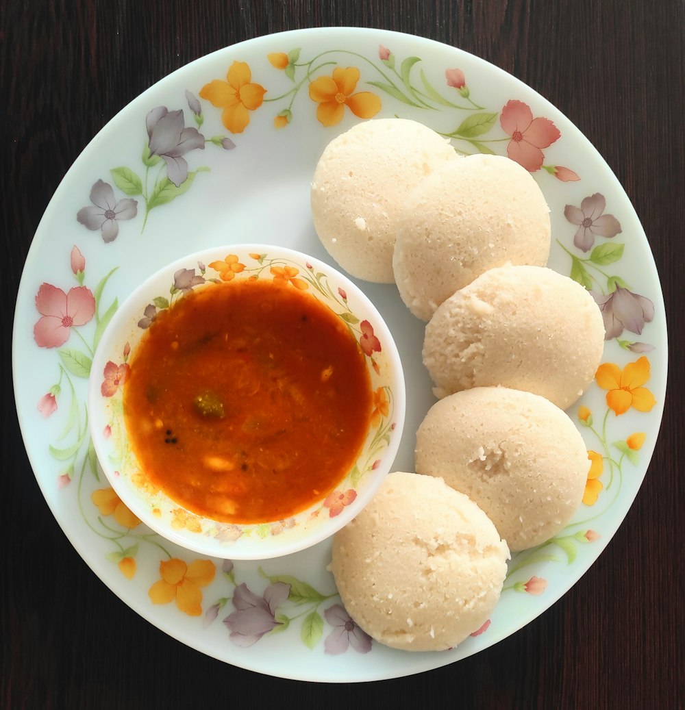 a white plate topped with three dumplings and a bowl of sauce